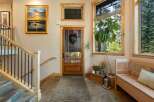Step into a welcoming entryway featuring a beautiful landscape painting above a wooden staircase with wrought iron railings.
