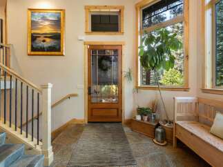 Step into a welcoming entryway featuring a beautiful landscape painting above a wooden staircase with wrought iron railings.