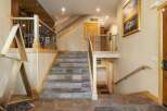 This stunning home features a grand staircase with slate tile risers and treads, complemented by a rustic wooden handrail and black metal balusters.