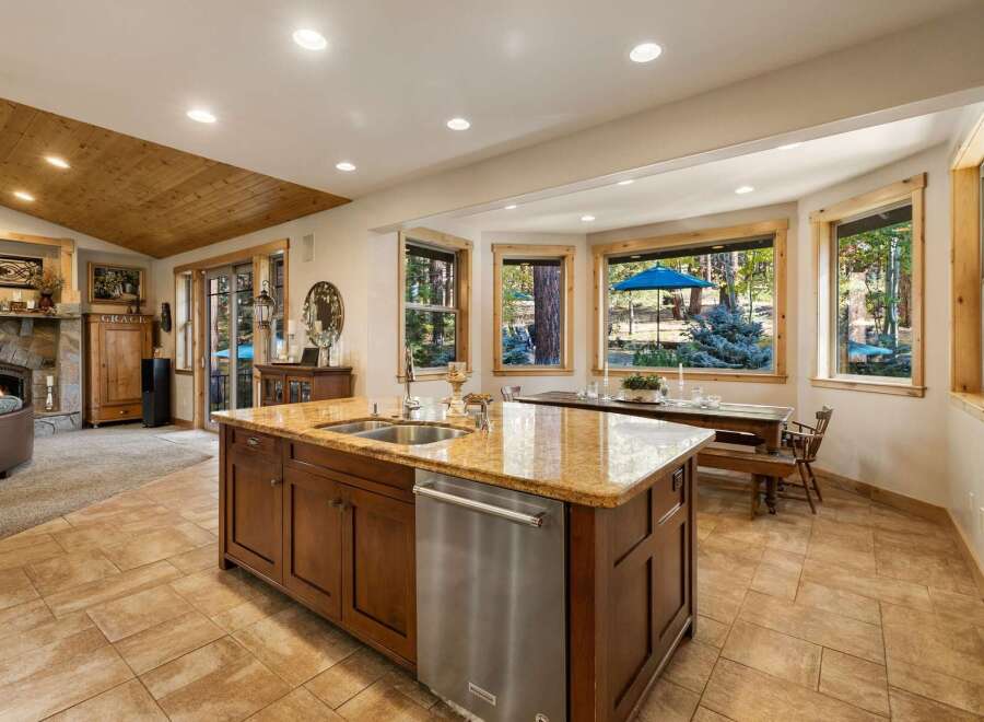 This spacious kitchen boasts a large island with granite countertops, a double sink, and a dishwasher, perfect for entertaining.
