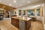 This spacious kitchen boasts a large island with granite countertops, a double sink, and a dishwasher, perfect for entertaining.