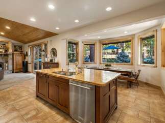 This spacious kitchen boasts a large island with granite countertops, a double sink, and a dishwasher, perfect for entertaining.