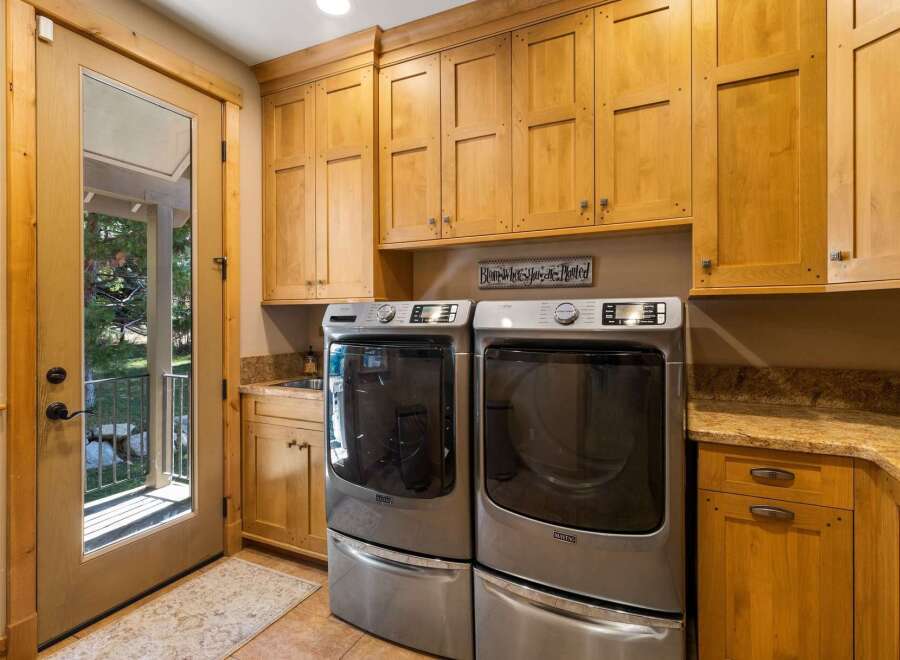 This spacious laundry room boasts ample storage with custom light wood cabinetry, perfect for organizing all your laundry essentials.