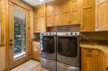 This spacious laundry room boasts ample storage with custom light wood cabinetry, perfect for organizing all your laundry essentials.