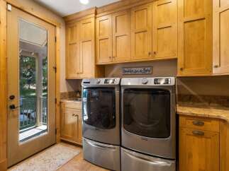 This spacious laundry room boasts ample storage with custom light wood cabinetry, perfect for organizing all your laundry essentials.