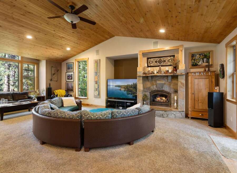 Experience the ultimate in rustic luxury with this stunning living room, featuring a grand stone fireplace and a vaulted wood-paneled ceiling.