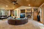 Experience the ultimate in rustic luxury with this stunning living room, featuring a grand stone fireplace and a vaulted wood-paneled ceiling.