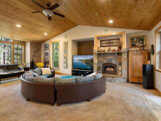 Experience the ultimate in rustic luxury with this stunning living room, featuring a grand stone fireplace and a vaulted wood-paneled ceiling.