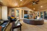 Experience rustic charm in this spacious living room, featuring a vaulted wood-paneled ceiling and a cozy stone fireplace.