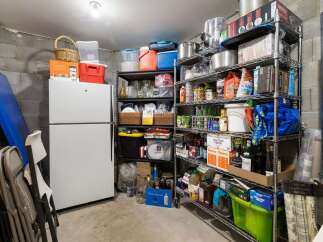 Discover ample storage solutions in this property's basement, featuring a large white refrigerator and extensive shelving units.