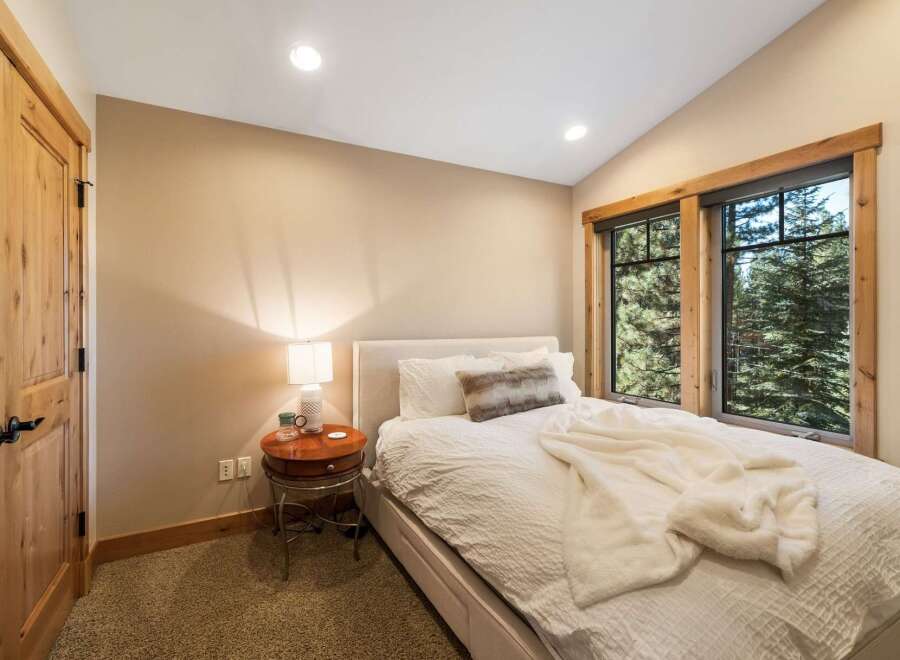 Experience cozy mountain living in this charming bedroom, featuring a comfortable bed adorned with plush white linens and a soft throw blanket.