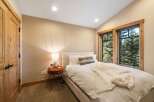 Experience cozy mountain living in this charming bedroom, featuring a comfortable bed adorned with plush white linens and a soft throw blanket.