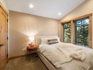 Experience cozy mountain living in this charming bedroom, featuring a comfortable bed adorned with plush white linens and a soft throw blanket.