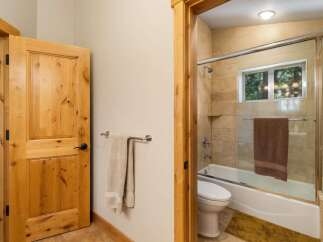 Step into this charming bathroom featuring a natural wood door and a sleek glass-enclosed shower.