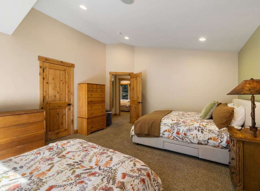 This spacious bedroom features two comfortable beds, each adorned with charming floral bedding and warm brown quilts.