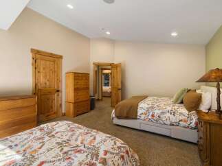 This spacious bedroom features two comfortable beds, each adorned with charming floral bedding and warm brown quilts.
