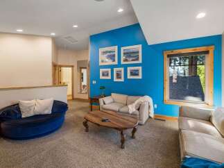 This spacious living area boasts a vibrant blue accent wall adorned with framed artwork, creating a focal point for the room.