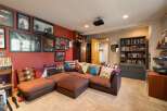 This entertainment room features a large, comfortable sectional sofa adorned with colorful throw pillows, perfect for movie nights or gatherings.