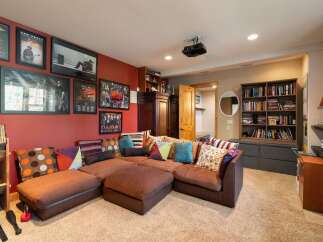 This entertainment room features a large, comfortable sectional sofa adorned with colorful throw pillows, perfect for movie nights or gatherings.