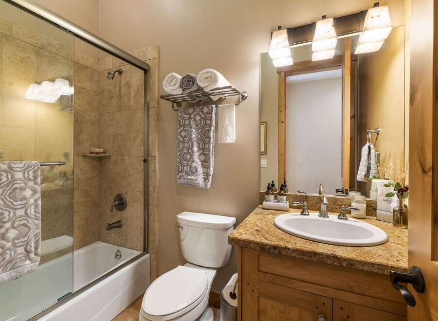 This charming bathroom features a spacious bathtub with a glass enclosure and tiled walls, perfect for a relaxing soak.