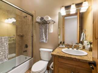 This charming bathroom features a spacious bathtub with a glass enclosure and tiled walls, perfect for a relaxing soak.