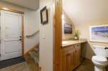 This charming bathroom features a wooden vanity with a granite countertop and a white sink, complemented by a large framed ski poster on the wall.