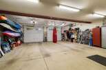 This spacious garage offers ample storage for all your recreational gear, including multiple paddleboards neatly stacked and a collection of skis ready for the slopes.