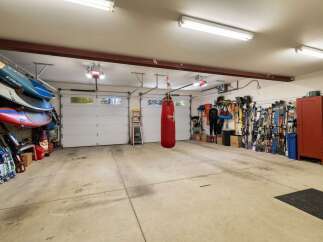 This spacious garage offers ample storage for all your recreational gear, including multiple paddleboards neatly stacked and a collection of skis ready for the slopes.