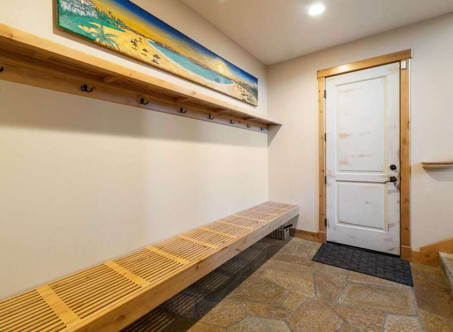 Welcome guests into this charming entryway featuring a long, slatted wooden bench perfect for removing shoes.