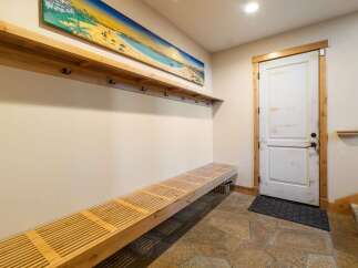 Welcome guests into this charming entryway featuring a long, slatted wooden bench perfect for removing shoes.