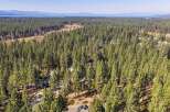 Discover this stunning aerial view showcasing a beautiful property nestled within a dense pine forest.
