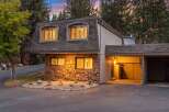 Nestled amongst tall pine trees, this charming home features a unique stone facade and a mansard roof.