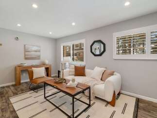 This inviting living room features a plush white sofa adorned with accent pillows and a cozy throw, perfect for relaxation.