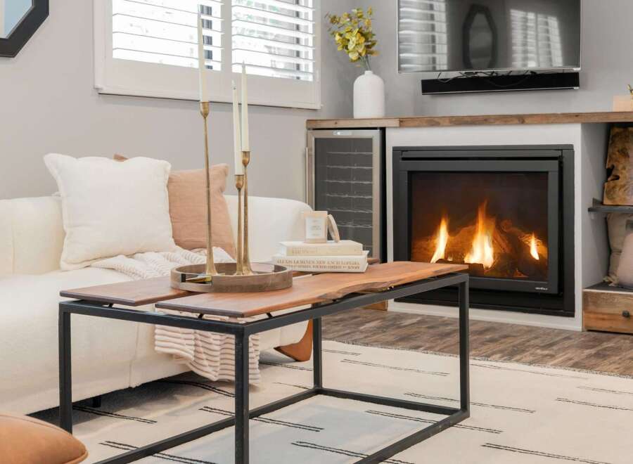 Cozy up by the fireplace in this inviting living room, featuring a plush white sofa adorned with accent pillows and a rustic live-edge coffee table.