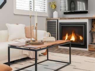 Cozy up by the fireplace in this inviting living room, featuring a plush white sofa adorned with accent pillows and a rustic live-edge coffee table.