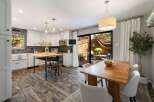 This modern kitchen features white cabinetry, a decorative backsplash, and a butcher block island with bar stools.