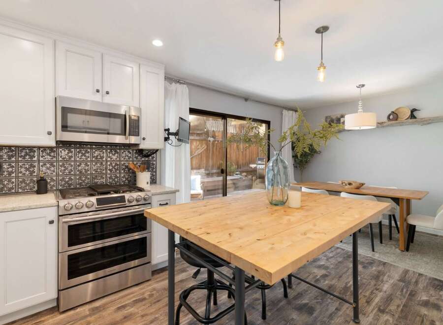 This modern kitchen features sleek white cabinetry, a stainless steel double oven, and a decorative tile backsplash.
