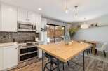 This modern kitchen features sleek white cabinetry, a stainless steel double oven, and a decorative tile backsplash.