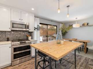 This modern kitchen features sleek white cabinetry, a stainless steel double oven, and a decorative tile backsplash.