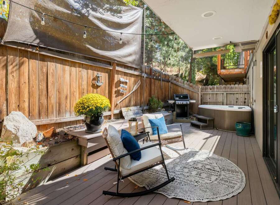 Enjoy outdoor living with this spacious deck featuring a relaxing hot tub and a built-in grill, perfect for entertaining.