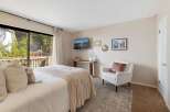 Experience serene living in this charming bedroom, featuring a plush bed adorned with cozy throws and pillows, perfect for relaxation.