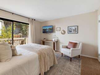 Experience serene living in this charming bedroom, featuring a plush bed adorned with cozy throws and pillows, perfect for relaxation.