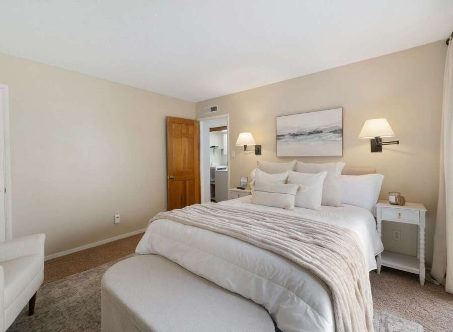 This inviting bedroom features a plush king-sized bed adorned with crisp white linens and a cozy, neutral-toned throw blanket.