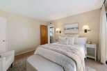 This inviting bedroom features a plush king-sized bed adorned with crisp white linens and a cozy, neutral-toned throw blanket.