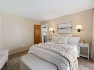 This inviting bedroom features a plush king-sized bed adorned with crisp white linens and a cozy, neutral-toned throw blanket.