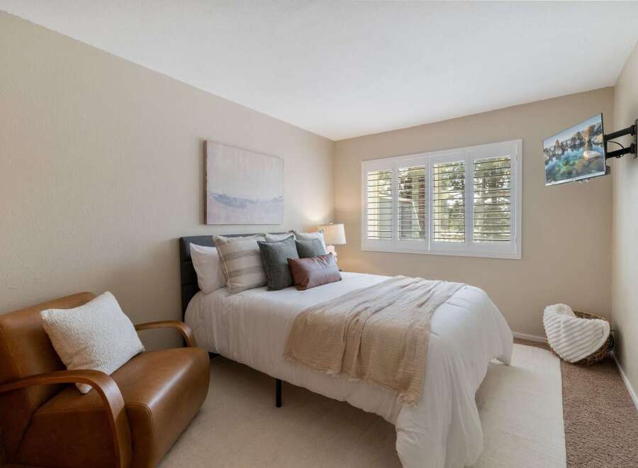 This inviting bedroom features a comfortable queen-size bed adorned with plush pillows and a cozy throw blanket, perfect for relaxation.