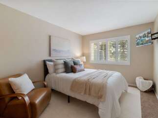 This inviting bedroom features a comfortable queen-size bed adorned with plush pillows and a cozy throw blanket, perfect for relaxation.