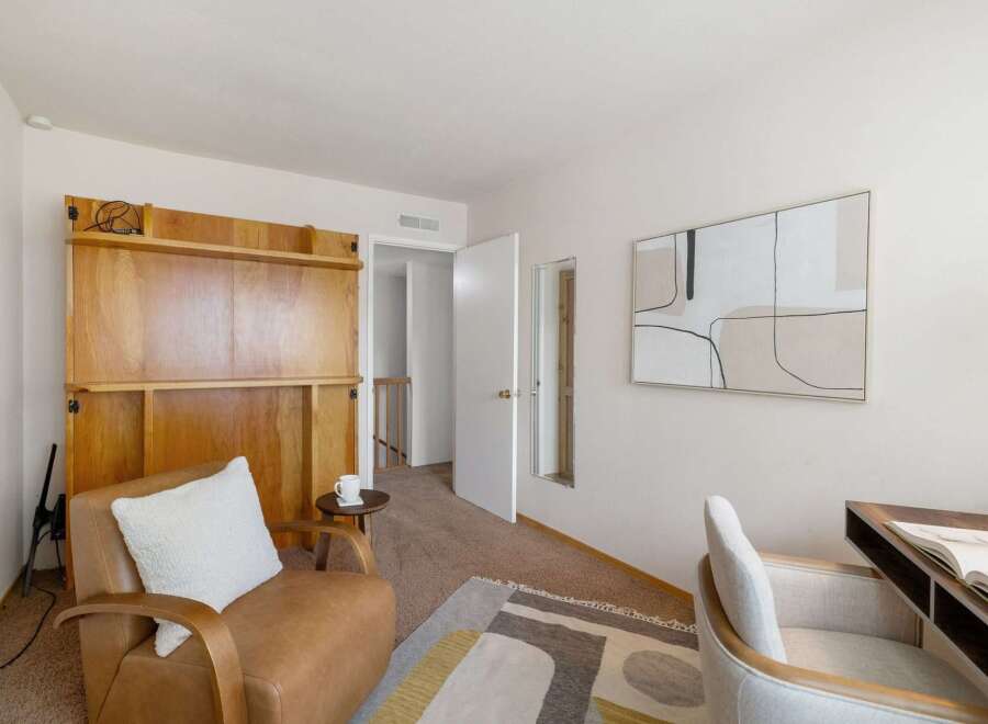 Discover this versatile room, perfect for a home office or guest space, featuring a comfortable leather armchair and a modern desk setup.