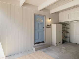 Step into this charming entryway featuring a welcoming light blue door adorned with a rustic bear and tree 'Welcome' sign.