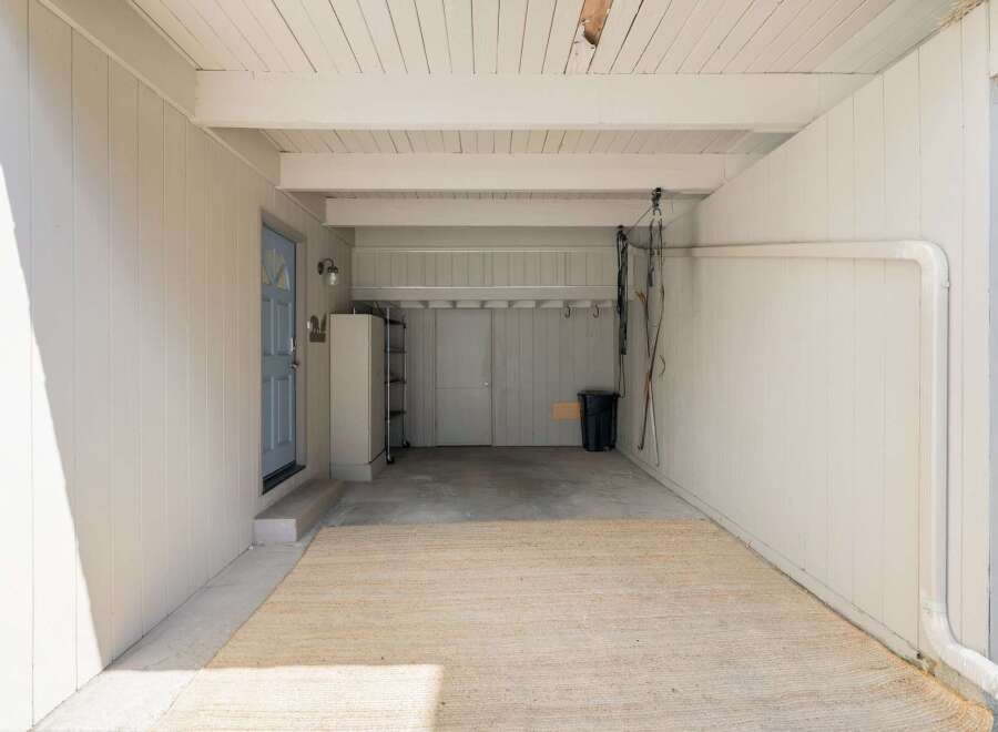 This spacious garage offers ample storage solutions with a tall metal shelving unit and overhead storage racks.